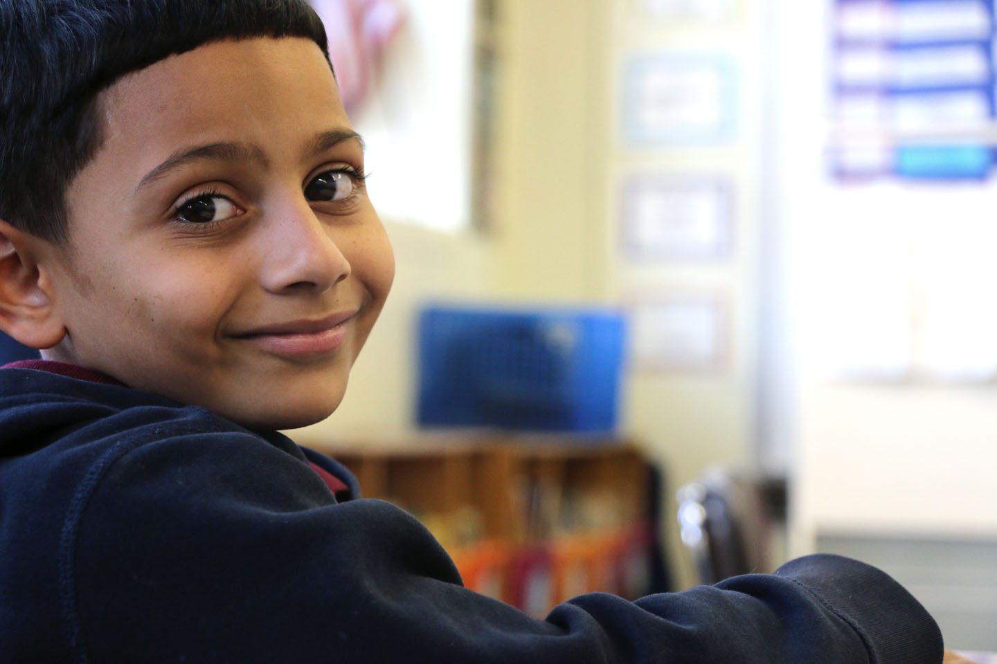 Middle school latino boy looking over shoulder smiling into camera