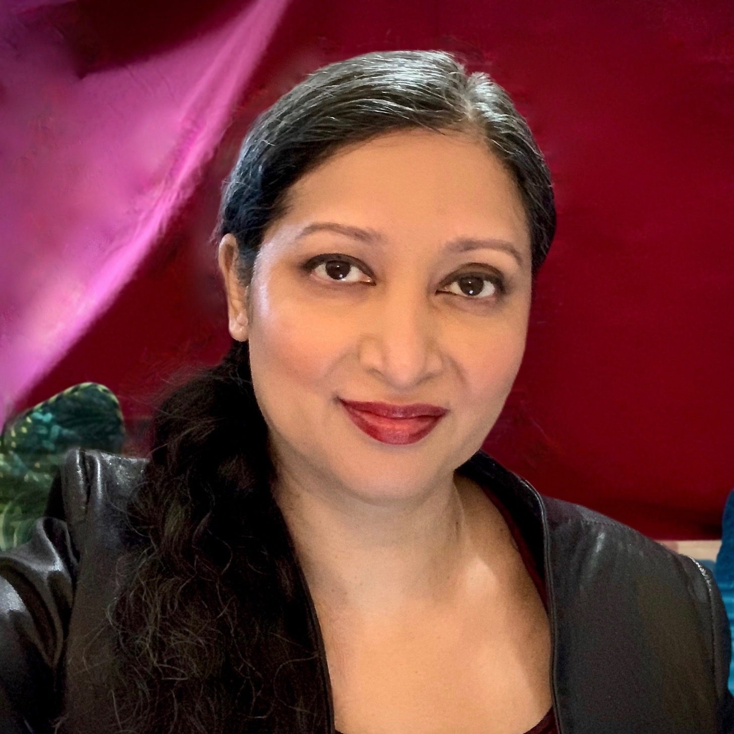 Portrait of person smiling at the camera dressed in black against a deep red background