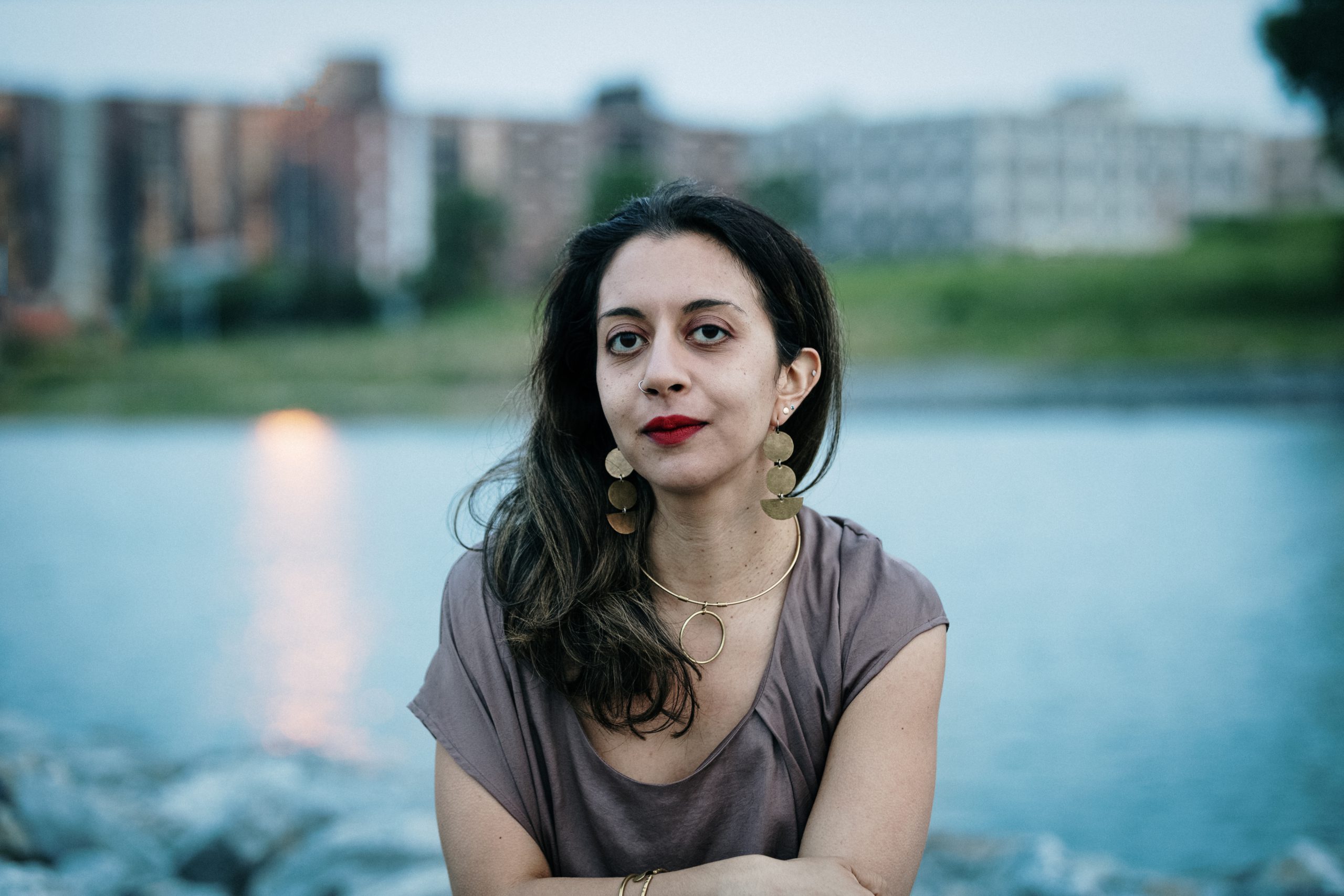 Portrait of woman looking at camera with a pond and Sunset Park, NYC in the background