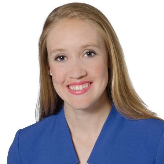 Blond woman in blue shirt smiling into camera