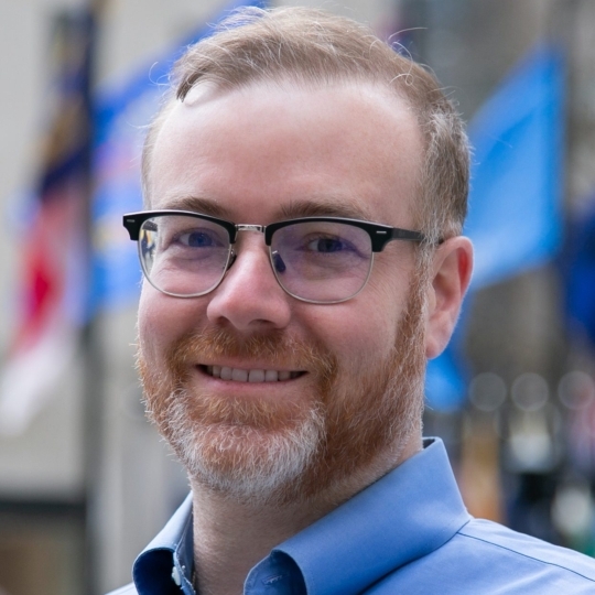 man with glasses smiling into camera
