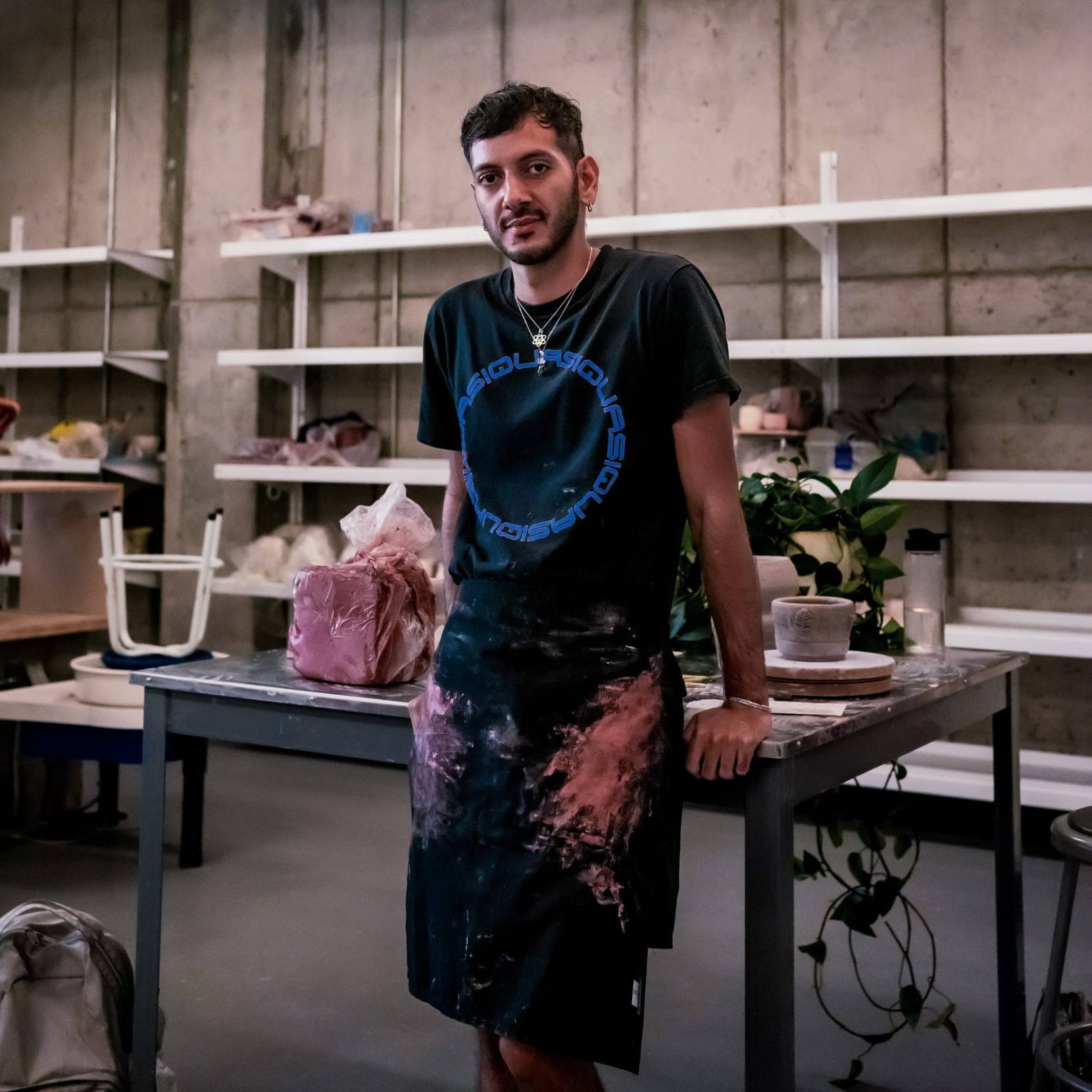 A photo of Jordany in an art studio leaning on a table