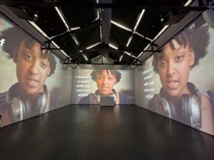 Gallery room with projection of a spoken word performance by high school student