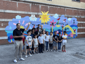 Group of youth at the Variety Boys and Girls Club of Astoria Queens in front of an exterior wall mural they painted about clean energy and protecting the planet