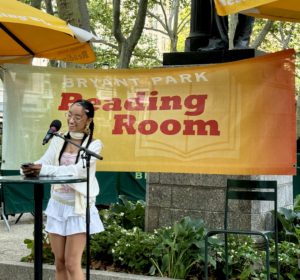 High school student reads their original poetry at NYC's Bryant Park Reading Room on a warm summer afternoon.