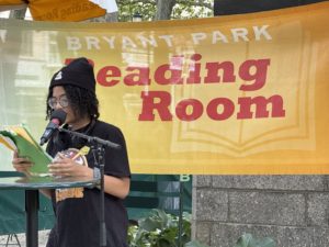 High school student reads original poetry at NYC's Bryant Park Reading Room on a warm summer day