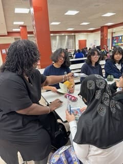 Author and students of a creative writing club meet in the cafeteria.