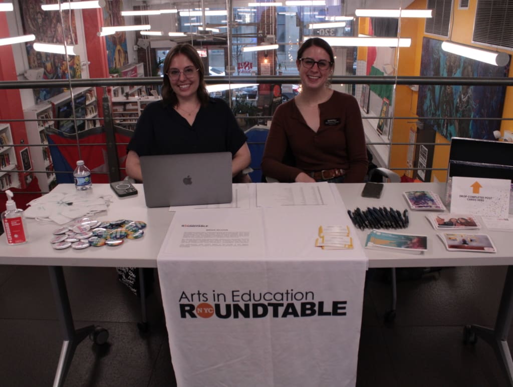 Two women sit at an information table at a panel on professionalism