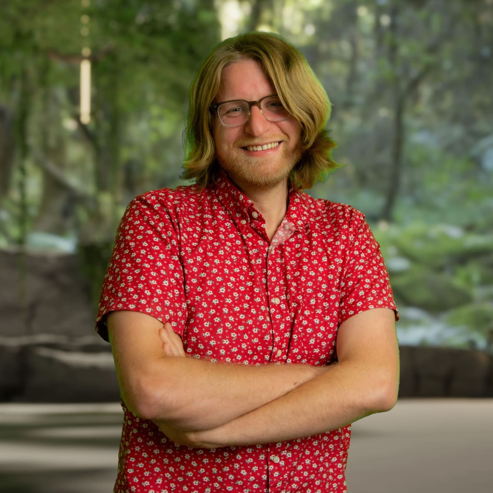 Man in red shirt with crossed arms looking at camera
