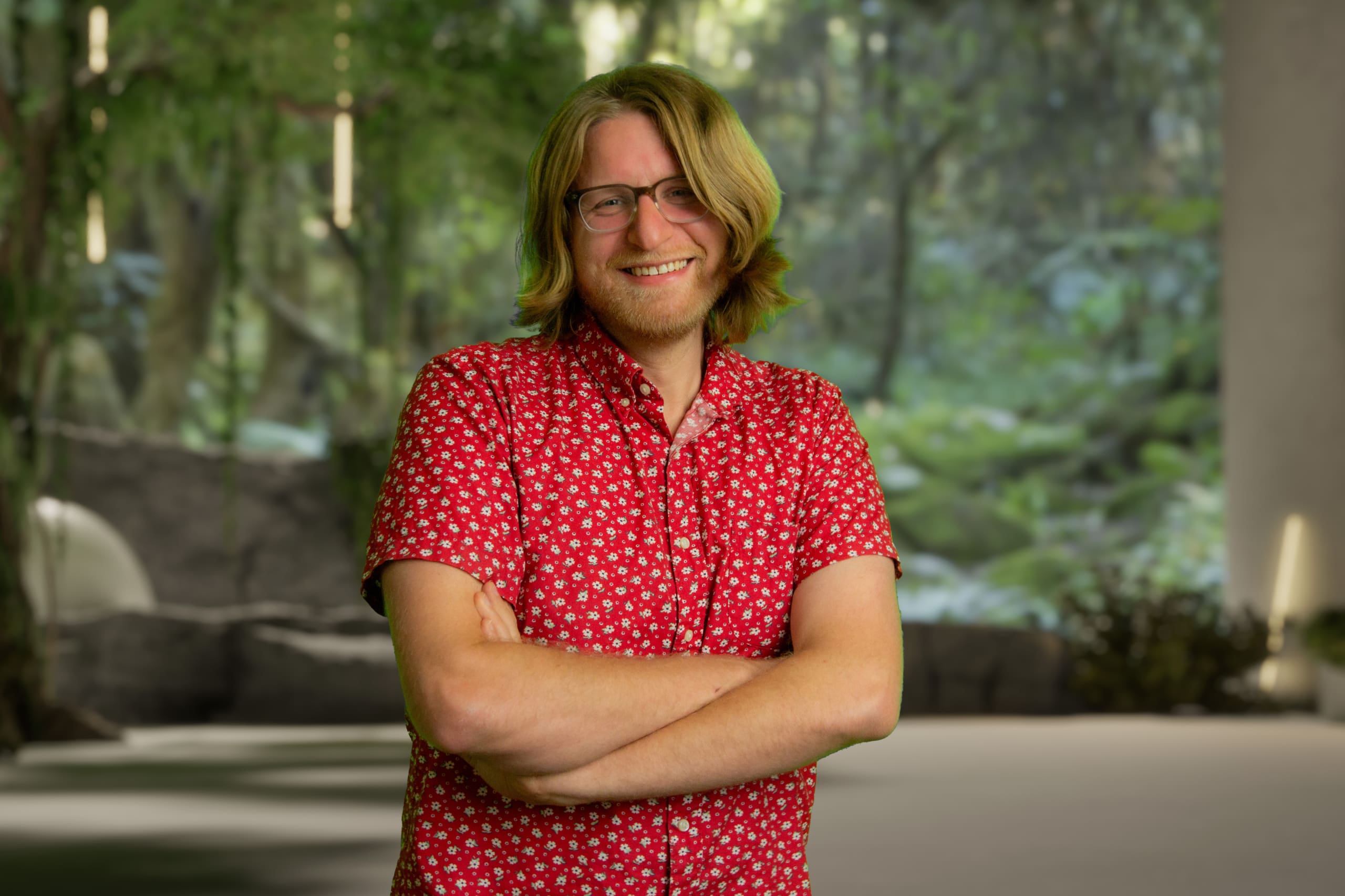 Man in red shirt with crossed arms looking at camera