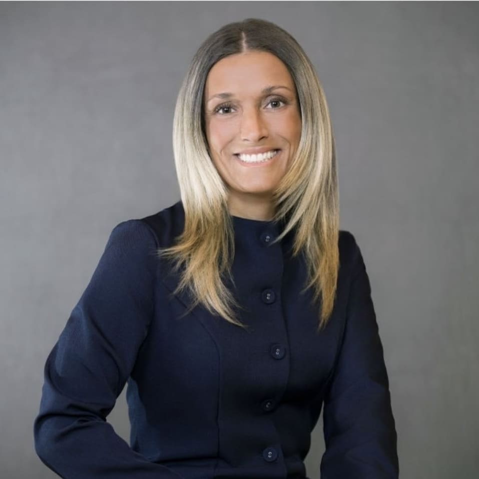 Woman smiling into camera in front of plain background
