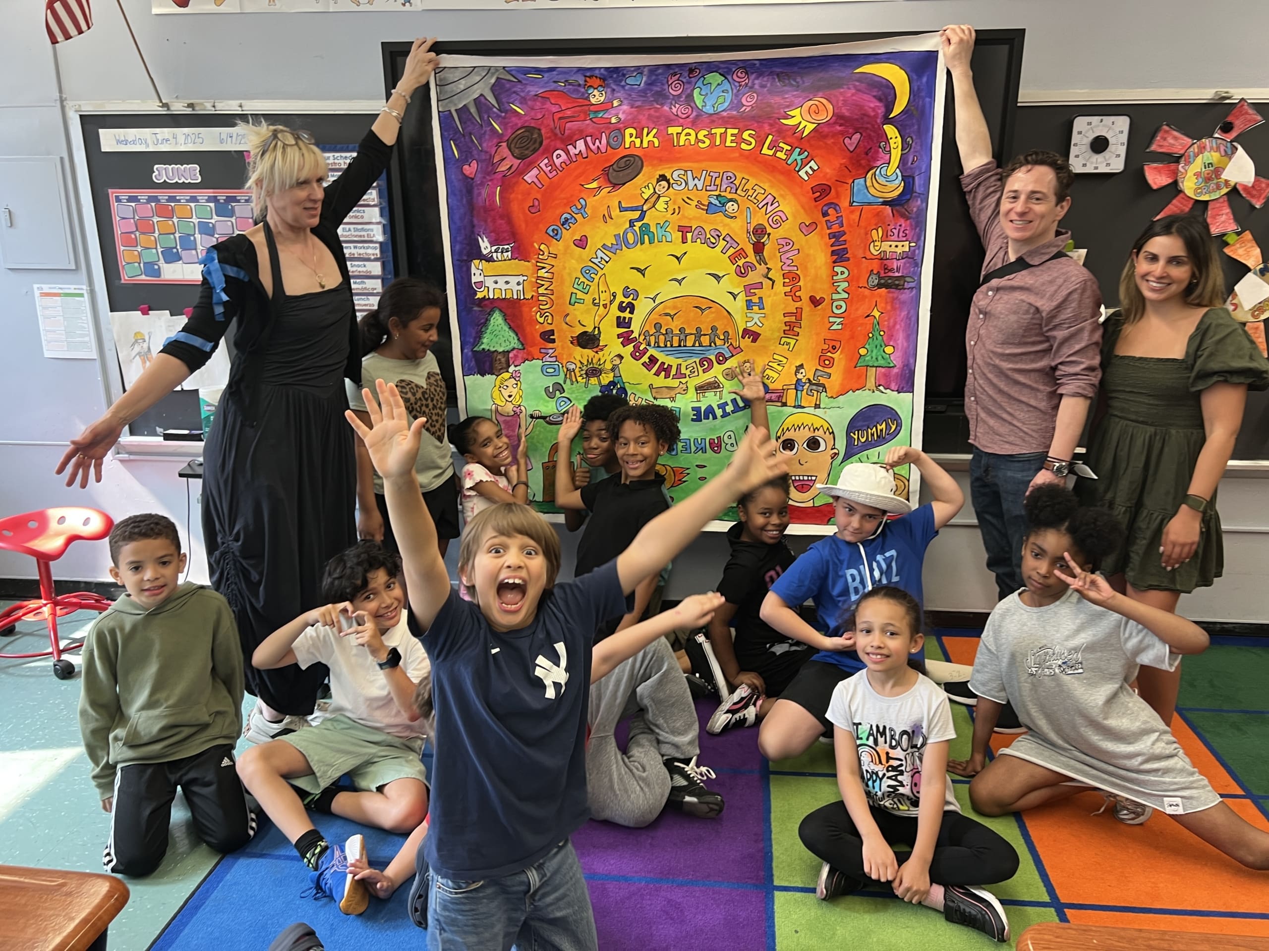 Young students in a classroom pulling faces with their teachers holding up there painting behind them