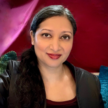 Portrait of woman smiling at the camera dressed in black against a deep red background