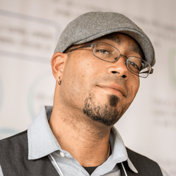Headshot of Daemond in a grey hat and glasses