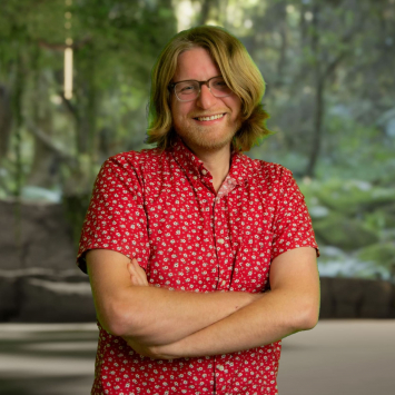 Man in red shirt with crossed arms looking at camera