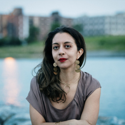 Portrait of woman looking at camera with a pond and Sunset Park, NYC in the background