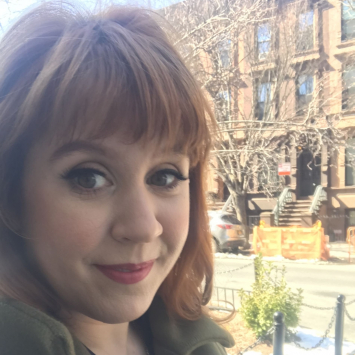 Close up of woman smiling from the stoop of a brownstone