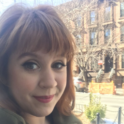 Close up of woman smiling from the stoop of a brownstone