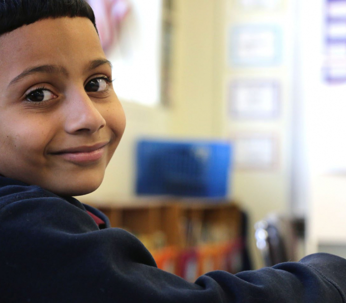 Middle school latino boy looking over shoulder smiling into camera