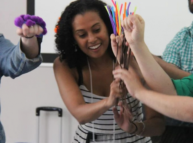 Young woman grasping pipecleaners as part of workshop exercise.